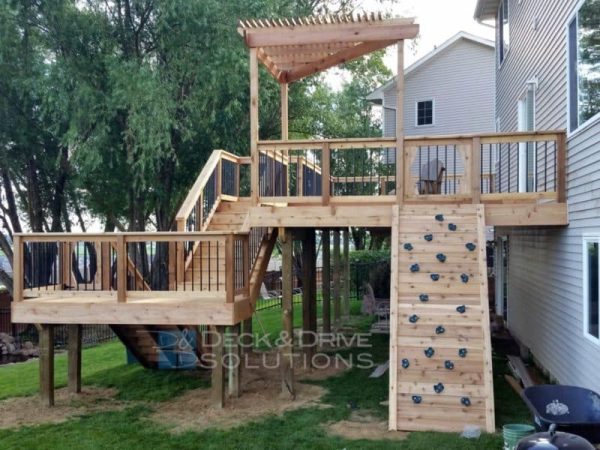 Custom Cedar Deck with triangle pergola, rock wall on deck and slide next to deck stairs