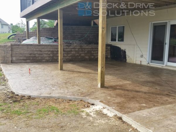 New Stamped Concrete patio under walkout deck with retaining wall