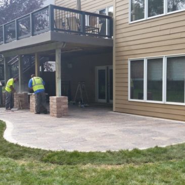 Landscapers at Work installing a paver patio under a walkout deck