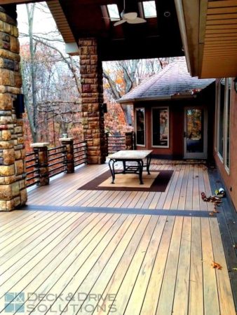 Triple picture frame board on composite deck with stone posts and metal rod rail, under partial covered roof