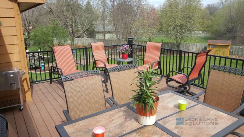Patio Table with flower pot and red chairs on new deck overlooking backyard