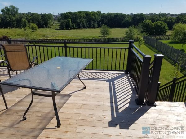 grass and natural field behind cedar deck with metal railing