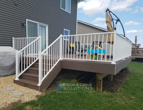 Composite deck with dark brown decking and white railing with stairs