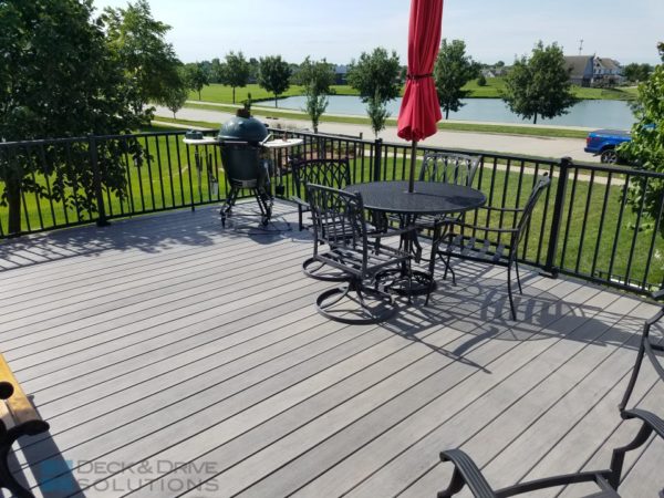 Gray composite decking with metal furniture and red umbrella
