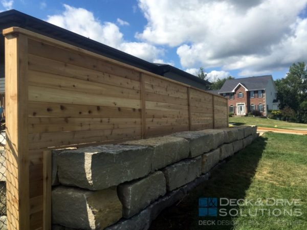horizontal cedar privacy fence with large block retaining wall