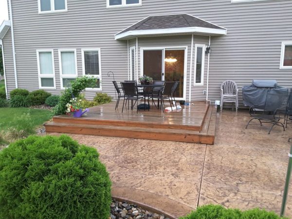 old wood platform deck with wrap around stairs on a stamped concrete patio