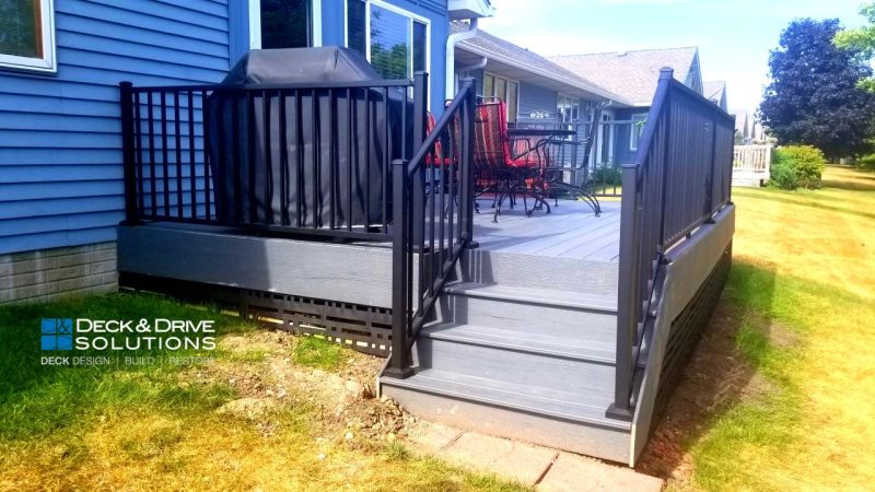 Under Deck Skirting with Modern Lattice Privacy Panels on a Timbertech Tropical Series Amazon Mist and Westbury Railing, Flowers on a deck with a blue house