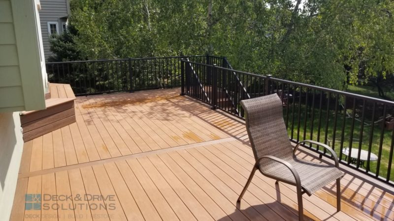 Composite Deck with black railing at back of house with large tree