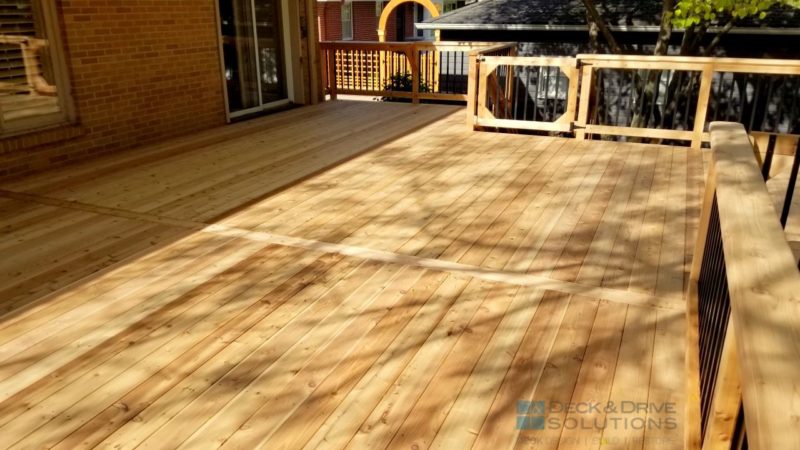 New cedar deck on brick house with center board and cedar post rail with metal spindles