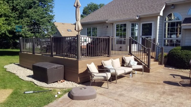 Stamped Concrete Patio with white chairs next to new composite deck in backyard