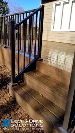 Deck stairs with black metal railing and dark brown composite decking