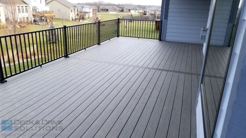 gray composite boards with black metal railing in backyard with neighbors