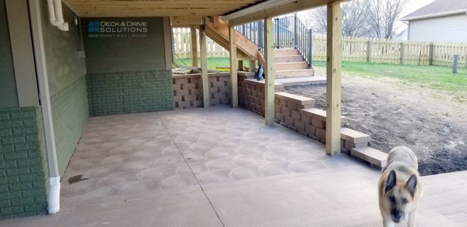 Under a deck with new concrete patio and retaining wall