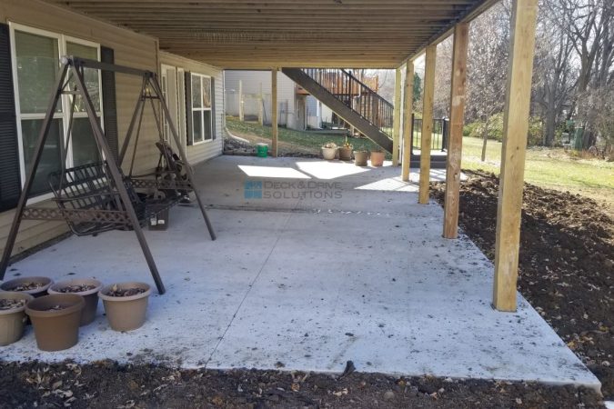 under a walkout deck with a fresh poured concrete patio