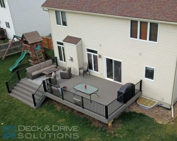 2 level composite deck with wide stairs, sitting area with Firepit below on lower deck and upper deck is eating area with grill