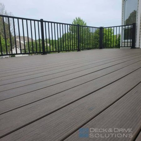 Close up picture of Timbertech Legacy Pecan Deck Boards with Westbury Aluminum Metal Railing behind on a gloomy day
