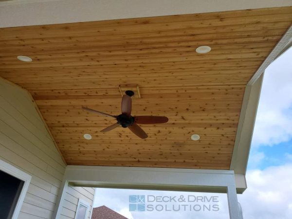 Cedar ceiling treatment with ceiling fan and led lights under a covered porch deck with white beams