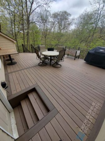 New Deck behind a garage with door access, Patio furniture out with trees behind
