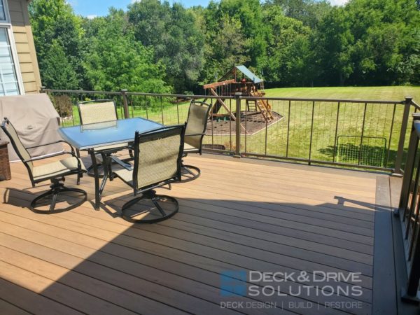 composite deck with table and chairs, westbury verticable rail and green grass and trees in background