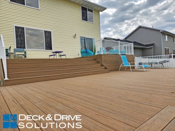 Multi Level Deck with composite fascia wall on yellow house with green chairs and white railing