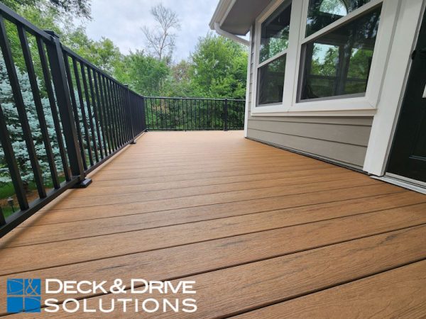 close up picture of timbertech antique leather decking with metal railing in a wooded backayard